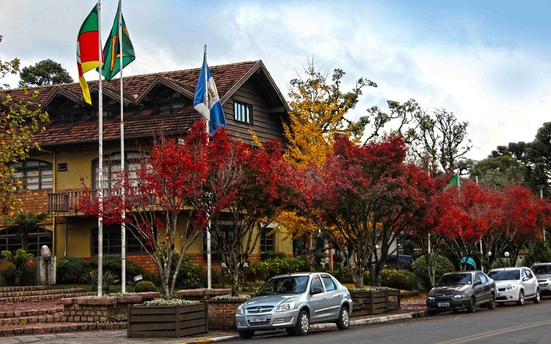 Rua de Gramado com árvores vermelhas e arquitetura em estilo alpino
