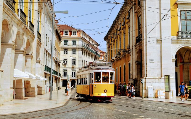 Elétrico amarelo em rua histórica de Lisboa